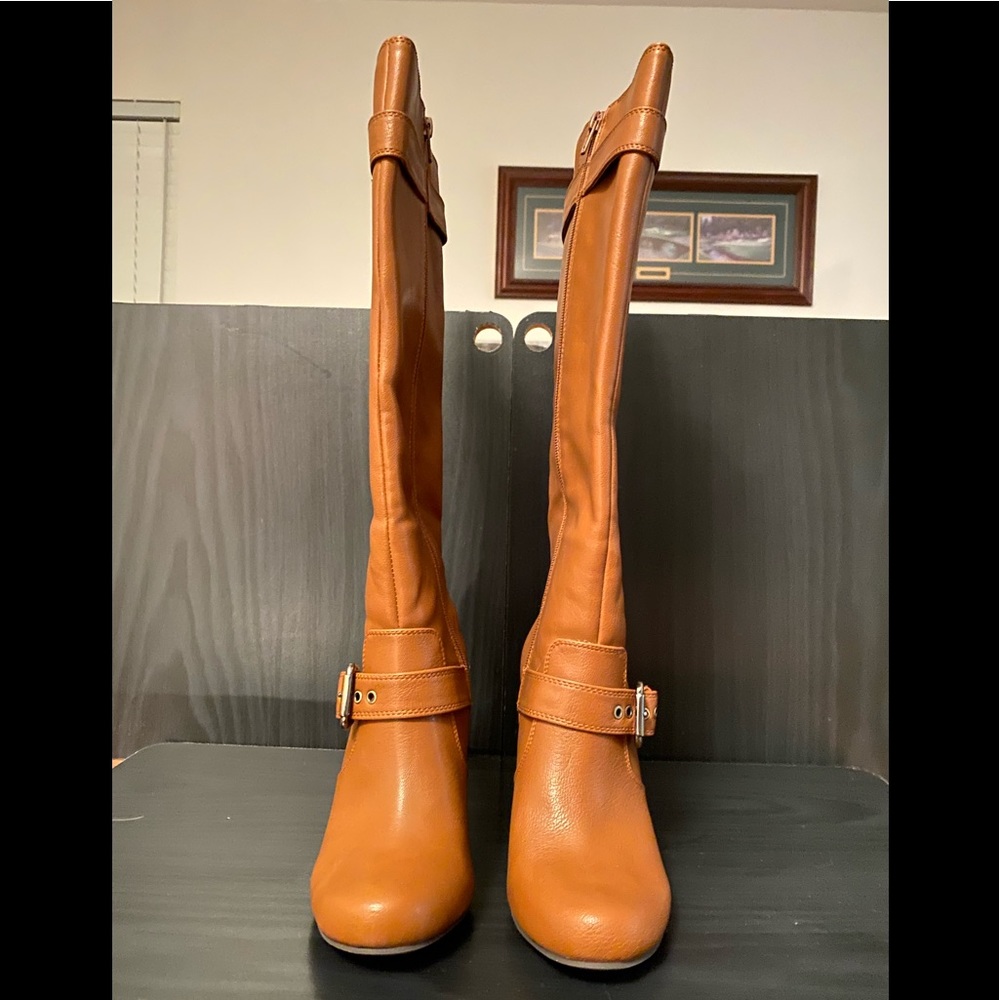 Tan heeled knee high boots with buckle embellishments